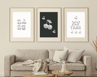 May include: Three framed prints featuring a silver cherry theme. The left print displays the numbers 2025 in silver balloons. The centre print has a black background with a silver cherry on a stem. The right print shows the words "MY YEAR" in silver balloons.