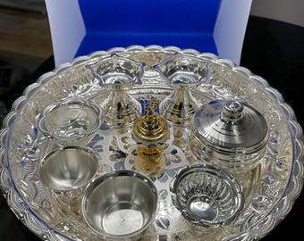May include: A silver tray with a decorative design, containing a variety of silver bowls and dishes, including two small bowls with a gold accent, a small lidded container, and a small incense burner.