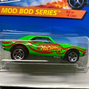 May include: Green and red Hot Wheels Mod Bod Series die-cast car. The car has a green body with red flame-like designs and the Hot Wheels logo. The packaging reads "#4 of 4 Cars."