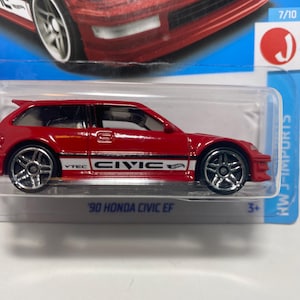 May include: A red '90 Honda Civic EF toy car with silver wheels. The car has white and black accents with the word "Civic" on the side. The toy car is in a clear plastic package with blue accents.