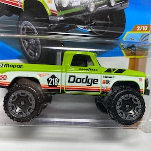 May include: A lime green and white Dodge pickup truck toy with black wheels. The truck has the number 218 on the side and the word "Dodge" in large white letters. The truck has the logos "Mopar", "Goodyear", and "Hemi".