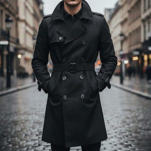 May include: A black trench coat with a double-breasted design, a belt, and a notched collar. The coat has a classic, tailored look, with a length that extends to the mid-thigh. The coat is worn over a black shirt.