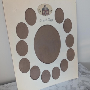 May include: Cream-colored photo frame with oval openings. The frame has a central large oval and smaller ovals arranged around it. An oval at the top features a schoolhouse illustration and the words "School Days".