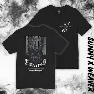 Könnte beinhalten: Schwarze T-Shirts mit grafischen Designs. Ein Shirt zeigt ein gehörntes Schädeldesign mit dem Wort "Fateless" und Text. Das andere Shirt hat ein Design einer Hand, die eine Perlenkette hält. Der Markenname "SUNNY X WEAVER" ist vertikal auf der rechten Seite aufgedruckt.