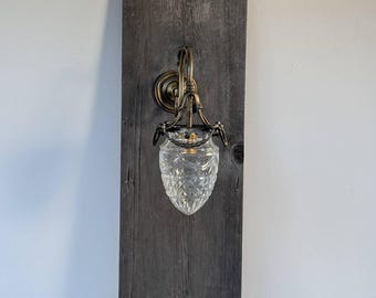 Väggmonterad mässingslampa med glasskärm som ger utrymmet en elegant touch och mjuk belysning.