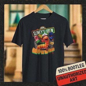 May include: Black t-shirt featuring a colorful graphic of cartoon worms with the text "SLIMEY'S KREW" and "GREW UP ON THE STREET." A red and white sticker in the bottom right corner reads "100% BOOTLEG UNAUTHORIZED ART."