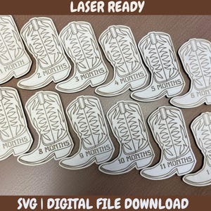 Può includere: Forme di stivali da cowboy in legno tagliate al laser, ciascuna etichettata con un mese da 1 a 11, più 1 anno. Gli stivali di colore chiaro presentano dettagli incisi, perfetti per le foto dei traguardi mensili di un bambino. È visibile anche il testo "LASER READY" e "SVG | DIGITAL FILE DOWNLOAD".
