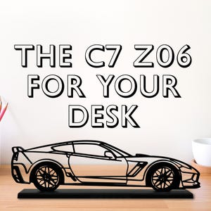 May include: Black and white line art of a Chevrolet Corvette Z06 on a black base. The text "THE C7 Z06 FOR YOUR DESK" is above the car.