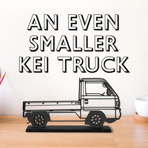 May include: A black metal silhouette of a small pickup truck with the text "An Even Smaller Kei Truck" above it.