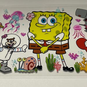 May include: A clear sticker featuring cartoon characters from the animated series, SpongeBob SquarePants. The sticker includes SpongeBob, Patrick Star, Sandy Cheeks, Mr. Krabs, Squidward Tentacles, Plankton, and Pearl, along with jellyfish and coral.