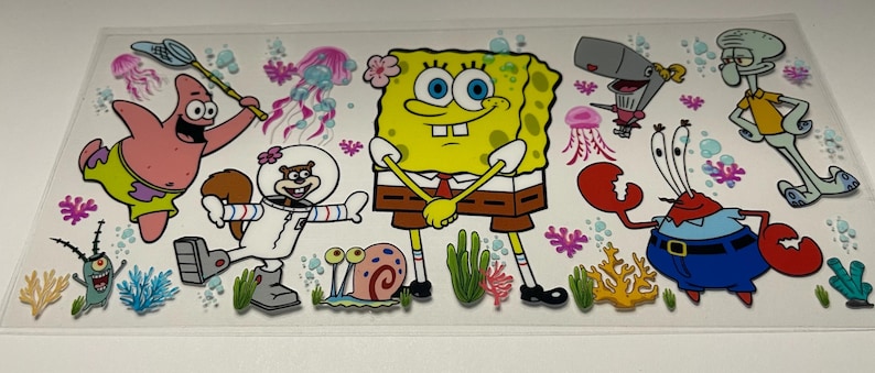 May include: A clear sticker featuring cartoon characters from the animated series, SpongeBob SquarePants. The sticker includes SpongeBob, Patrick Star, Sandy Cheeks, Mr. Krabs, Squidward Tentacles, Plankton, and Pearl, along with jellyfish and coral.