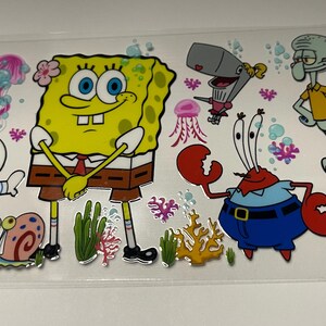 May include: A clear sticker sheet featuring cartoon characters from the animated series, including SpongeBob SquarePants, Patrick Star, Sandy Cheeks, Squidward Tentacles, Mr. Krabs, and Pearl. The characters are in bright colors with a cartoon style.