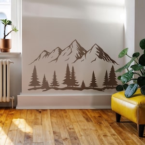 May include: A brown mountain and forest wall decal. The decal features a mountain range with several peaks and a line of pine trees at the base. The design is a silhouette, creating a minimalist and natural aesthetic.