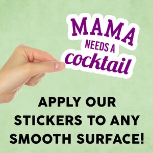 May include: A white sticker with purple text that reads "Mama needs a cocktail". A hand is holding the sticker up against a green background. The text "Apply our stickers to any smooth surface!" is printed below the sticker.