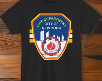 May include: Black t-shirt featuring the Fire Department City of New York emblem. The emblem is a shield shape with a blue background, the words "Fire Department City of New York" in white, and a red flame symbol.
