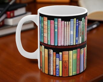 May include: White ceramic mug featuring a bookshelf design with rows of colorful books. The books have various colors and sizes, with the title "The Cat Climbs" visible on one. The mug has a white handle and is set on a wooden surface.