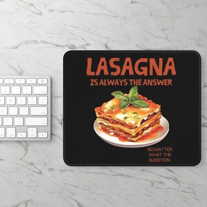 May include: A rectangular black mouse pad featuring a graphic of a layered lasagna on a white plate topped with green basil leaves. The text reads LASAGNA IS ALWAYS THE ANSWER NO MATTER WHAT THE QUESTION in orange lettering against the black background.