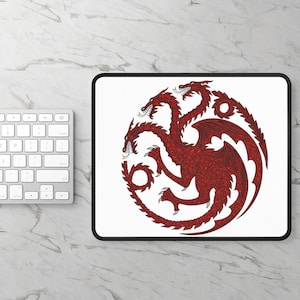 May include: A rectangular mouse pad with a white background and a black border. Centered on the pad is a circular graphic featuring a three-headed red dragon with intricate line work, depicted in a coiled position with wings spread wide.