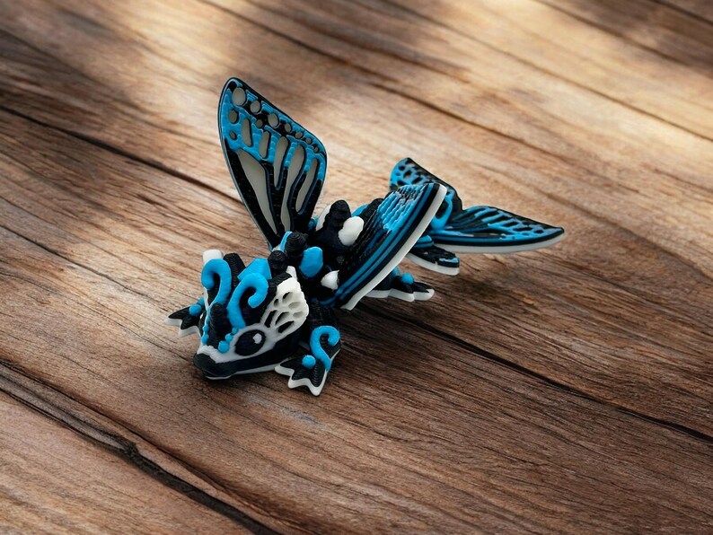 May include: A blue, black, and white 3D puzzle of a dragon with wings. The dragon is posed with its wings spread and its head tilted down.