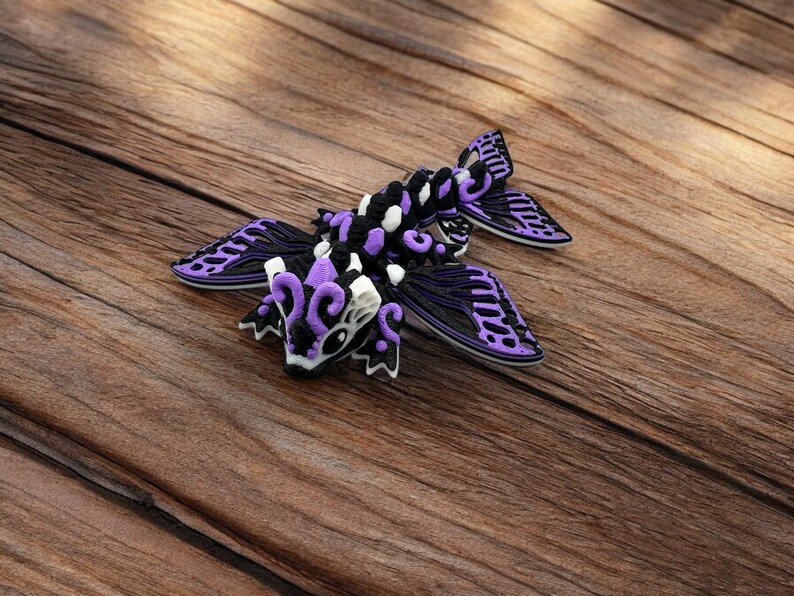 May include: A purple and black dragon figurine with intricate details and white accents. The dragon has wings and a long tail.
