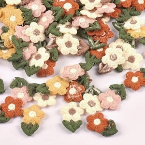 May include: Embroidered flower appliques in cream, pink, orange, and yellow. Each flower has a detailed design with green leaves, ideal for crafting and embellishments. The appliques are suitable for various craft projects.