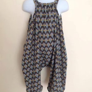 May include: A blue and brown patterned jumpsuit with thin straps. The jumpsuit has a loose fit and a gathered neckline.