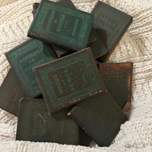 May include: A collection of antique books with dark green covers. The titles include "A Dream of John Ball", "Words of Jesus, Vol. 11", and "A Compdy of Errors". The books are stacked on a white, textured surface.