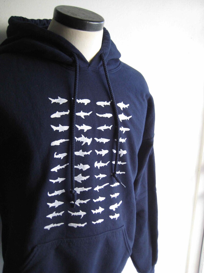 May include: A navy blue hooded sweatshirt with a white graphic print of a school of fish. The sweatshirt has a drawstring hood and a kangaroo pocket.