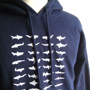 May include: A navy blue hooded sweatshirt with a white graphic print of a school of fish. The hoodie has a drawstring hood and long sleeves.