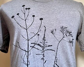 Op de afbeelding: Een heidekleurig T-shirt met een zwarte silhouetprint van vier verschillende wilde planten.