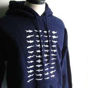 May include: A navy blue hooded sweatshirt with a white graphic of a school of fish on the front.