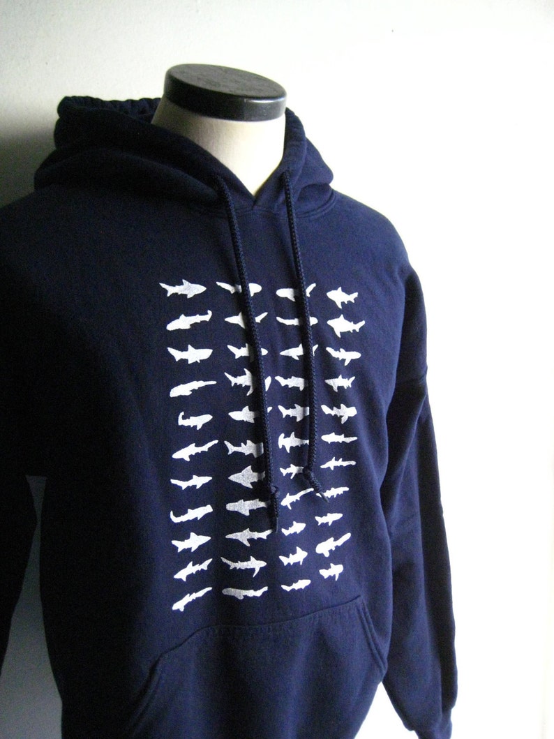 May include: A navy blue hooded sweatshirt with a white graphic of a school of fish on the front.