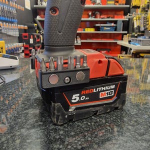 May include: A black and red cordless drill with a 5.0 Ah REDLITHIUM M18 battery. The drill has a magnetic bit holder with a variety of bits attached.