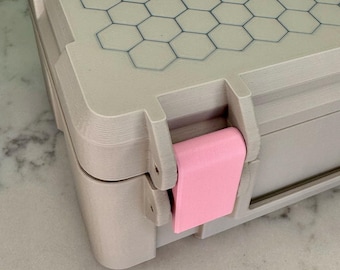 May include: A beige plastic storage case with a honeycomb pattern on the lid and a pink latch.