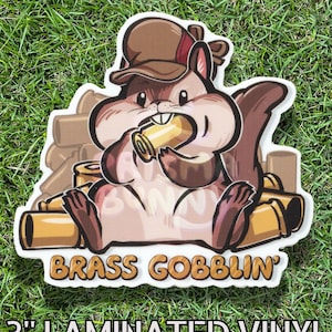 May include: A 3-inch laminated vinyl sticker featuring a cartoon squirrel wearing a hat and holding a brass object. The sticker has the text "BRASS GOBLIN" and is set against a green grass background.