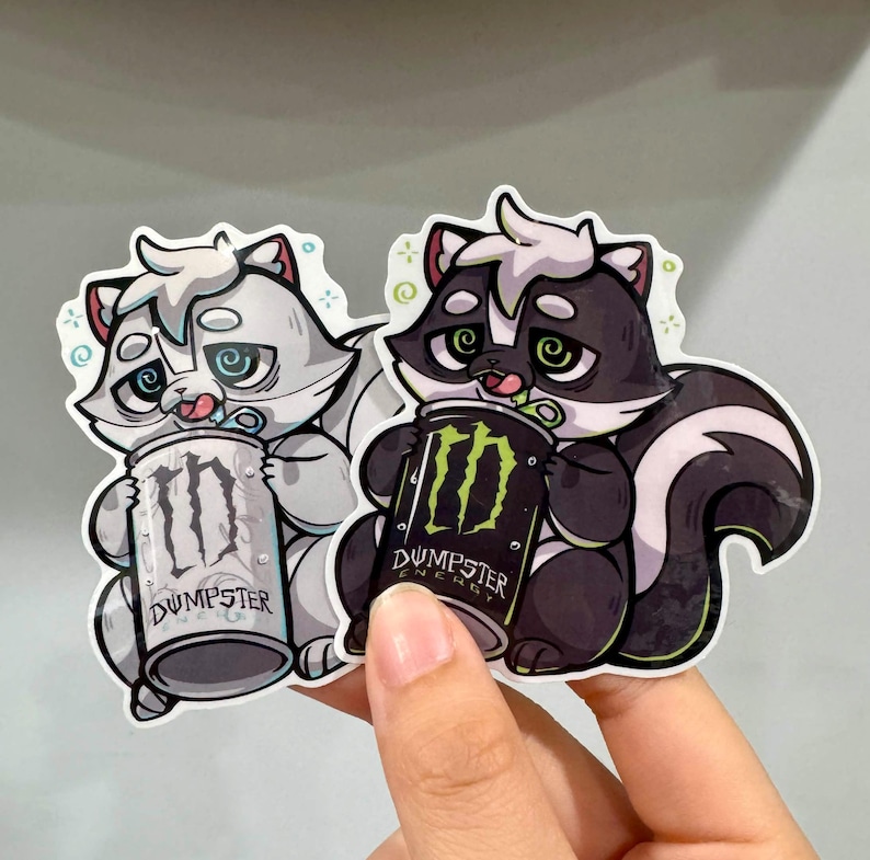 May include: Two stickers featuring cartoon skunks holding energy drink cans. One skunk is gray and white, the other is black and white. The cans read "Dumpster" and have a green logo.