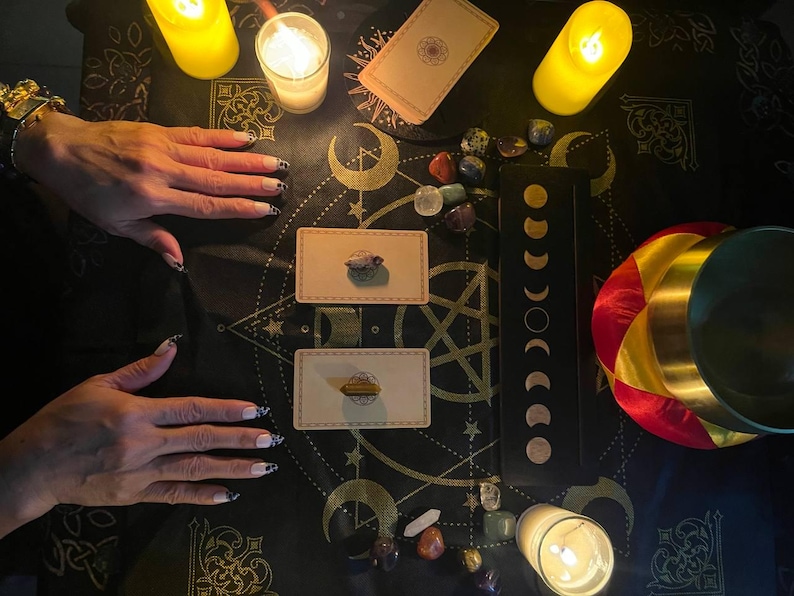 Pu&ograve; includere: Una tovaglia da altare nera con motivi celesti dorati, due carte dei tarocchi sormontate da cristalli, una tavola delle fasi lunari nera, gemme levigate, tre candele a colonna gialle accese e una campana tibetana con bordo dorato.