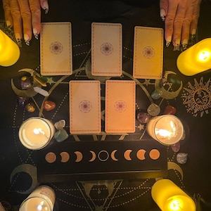 May include: A tarot card reading spread with six cards laid out on a black surface with a moon phase design. There are candles and crystals surrounding the cards.