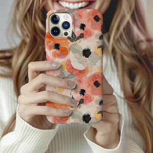 May include: A phone case with a floral design featuring pink, orange, and white flowers on a cream background. The case has a cutout for the camera lens.