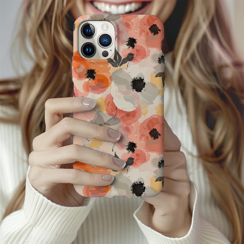 May include: A phone case with a floral design featuring pink, orange, and white flowers on a cream background. The case has a cutout for the camera lens.