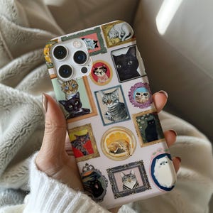 May include: A phone case featuring a collage of framed cat portraits in various styles. The case has a light pink background and includes images of black, gray, and orange cats. The frames are in different shapes and colors, adding a whimsical touch to the design.