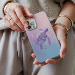 May include: A pink and blue gradient phone case with a floral design featuring a sea turtle. The turtle is surrounded by flowers and butterflies.