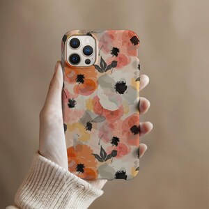 May include: A phone case with a floral pattern featuring pink, orange, and white flowers with black accents. The case has a cutout for the camera lens.