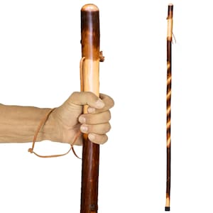 May include: A wooden walking stick with a dark brown finish and a lighter wood section. The stick has a leather strap and a rounded top. A second stick with a spiral design is also shown.