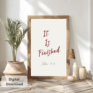 May include: A digital download of a printable wall art print with a white background and a wooden frame. The print features the text "It Is Finished" in red cursive font with the scripture reference "John 11:30" below.