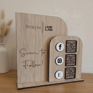 May include: Wooden display stand with the text "Scan to Follow!" and social media icons for Facebook, Instagram, and Etsy, each with a corresponding QR code. The stand also features the "Bespoke Laser Lab" logo.