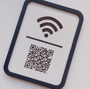 May include: A rectangular sign with a black border features a Wi-Fi symbol above a horizontal line and a QR code below. The design is in brown against a white background.