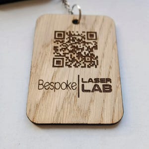 May include: A wooden keychain with a laser-engraved QR code and the text "Bespoke | LASER LAB".