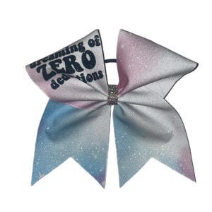 May include: A white and blue glitter cheer bow with the text "dreaming of ZERO deductions" in black.