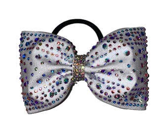 May include: A white sparkly hair bow with iridescent rhinestones and a silver band in the center.